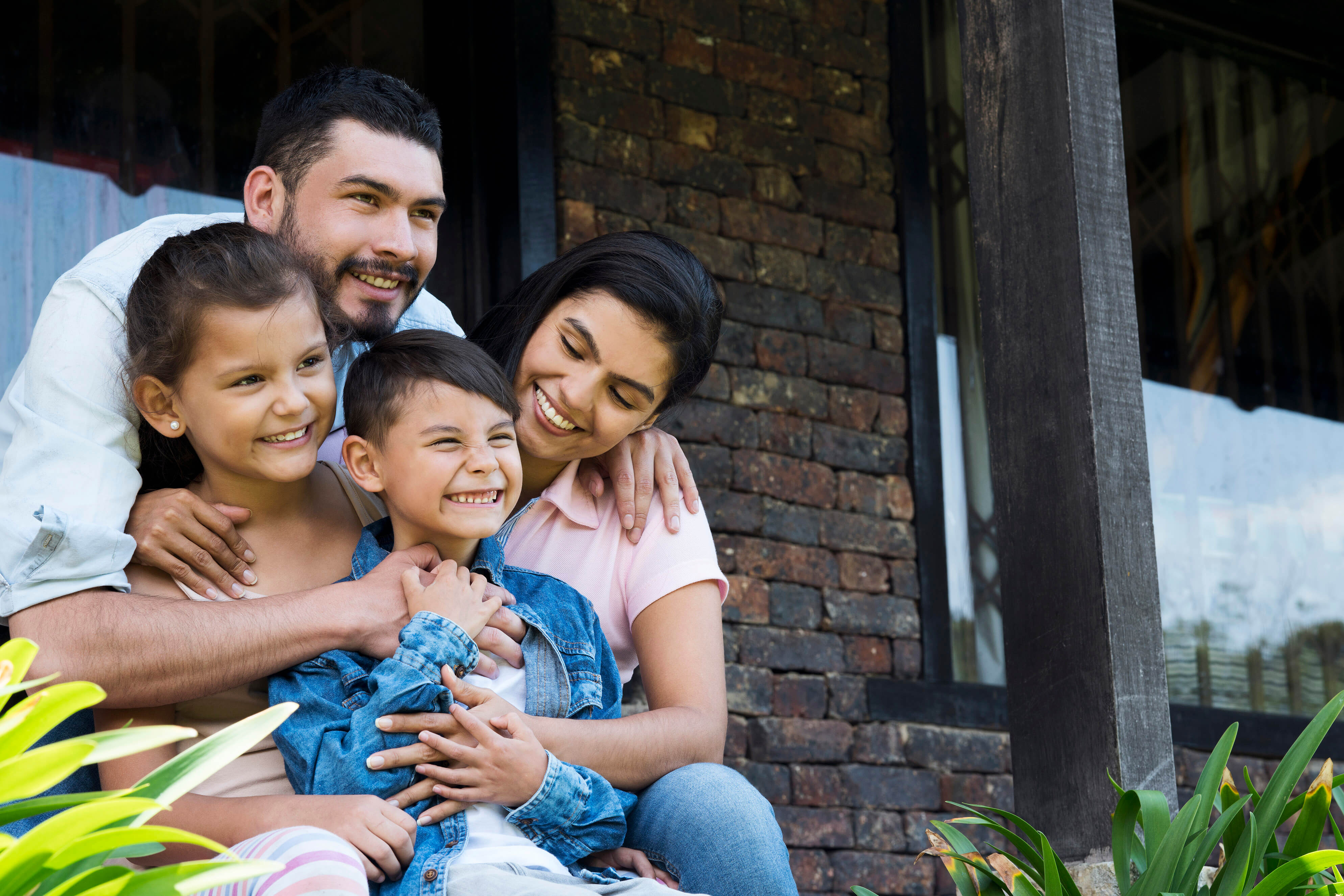 A father, mother, daughter, and son sitting outside together on a porch