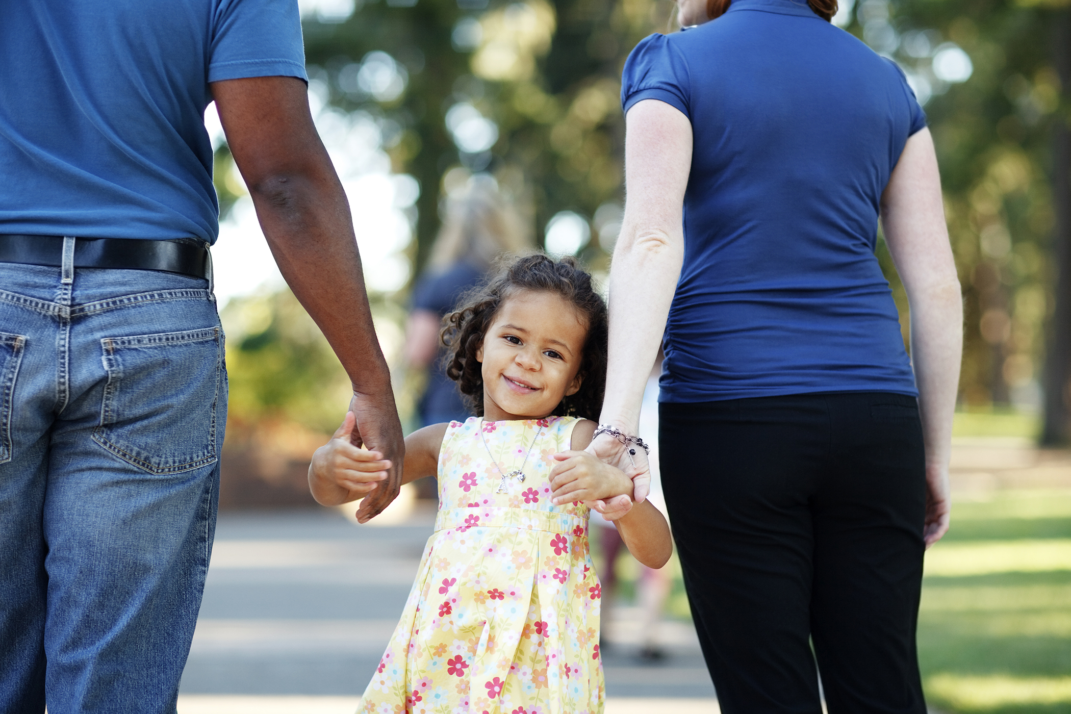 Dos adultos tomados de la mano con una niña