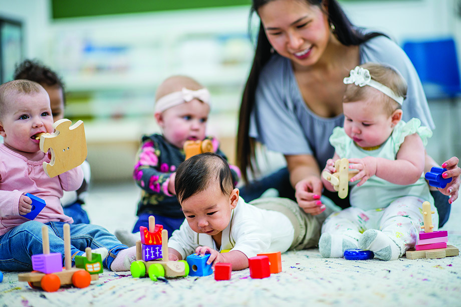 Child care provider sitting on the floor with four children