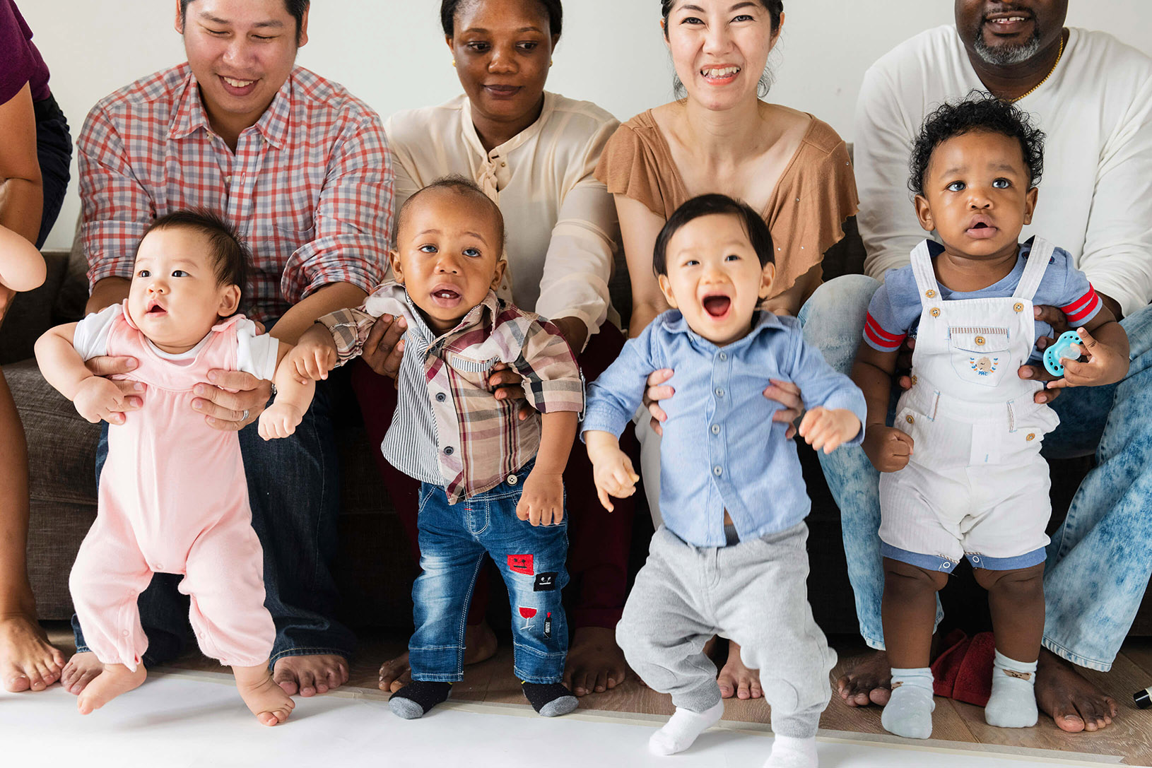 Four parents holding up their infants all in a row