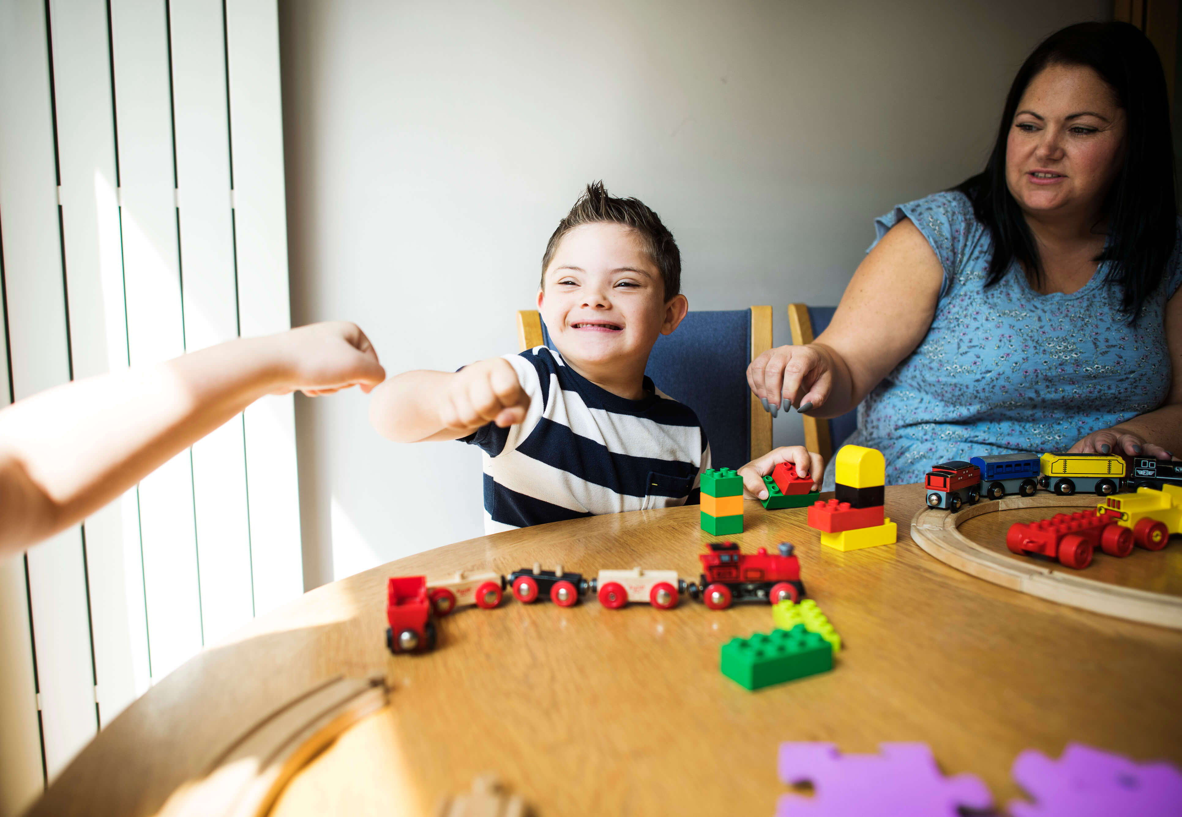 Student giving knuckles to teacher while playing with blocks