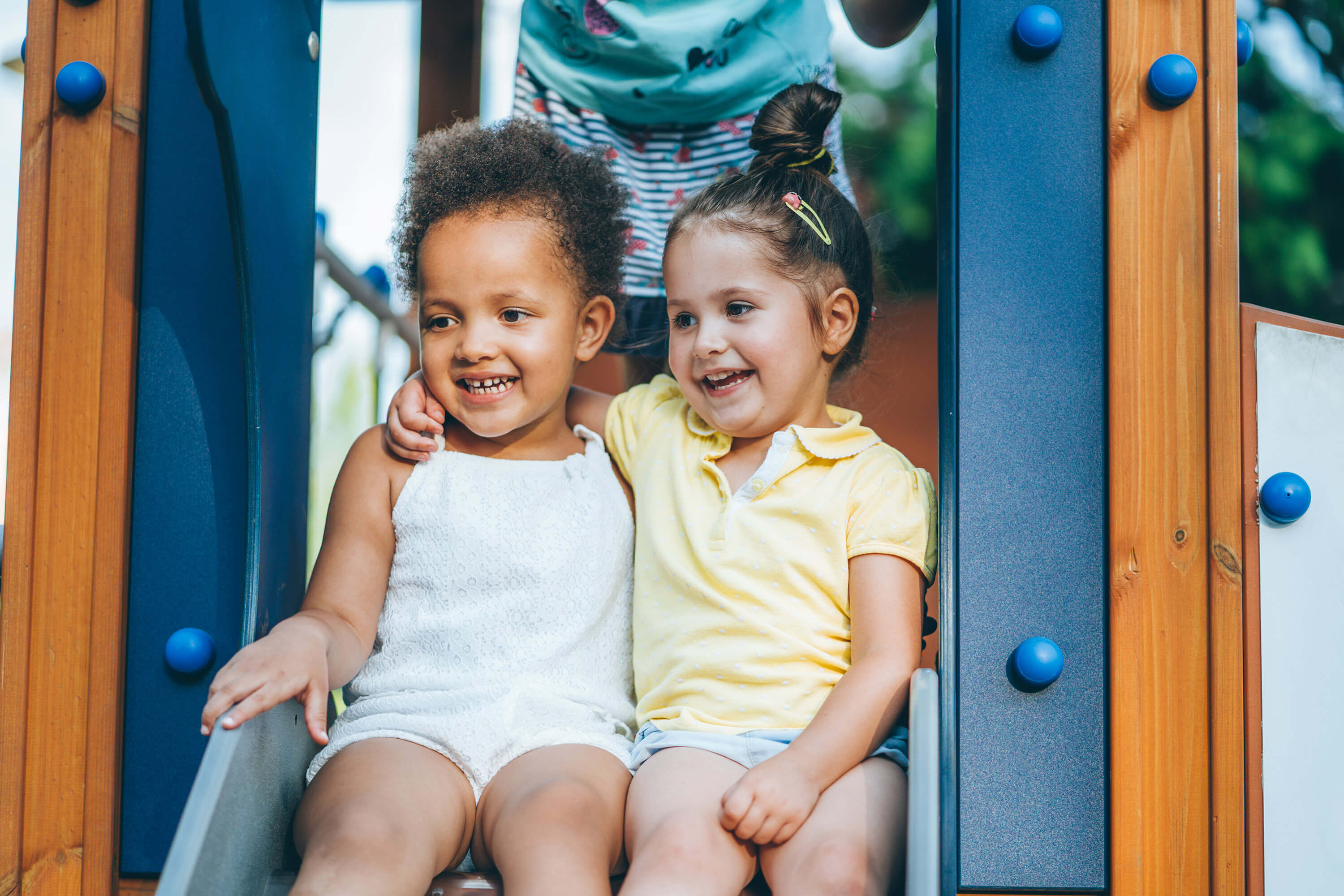 Two preschoolers sitting at the top of a slide