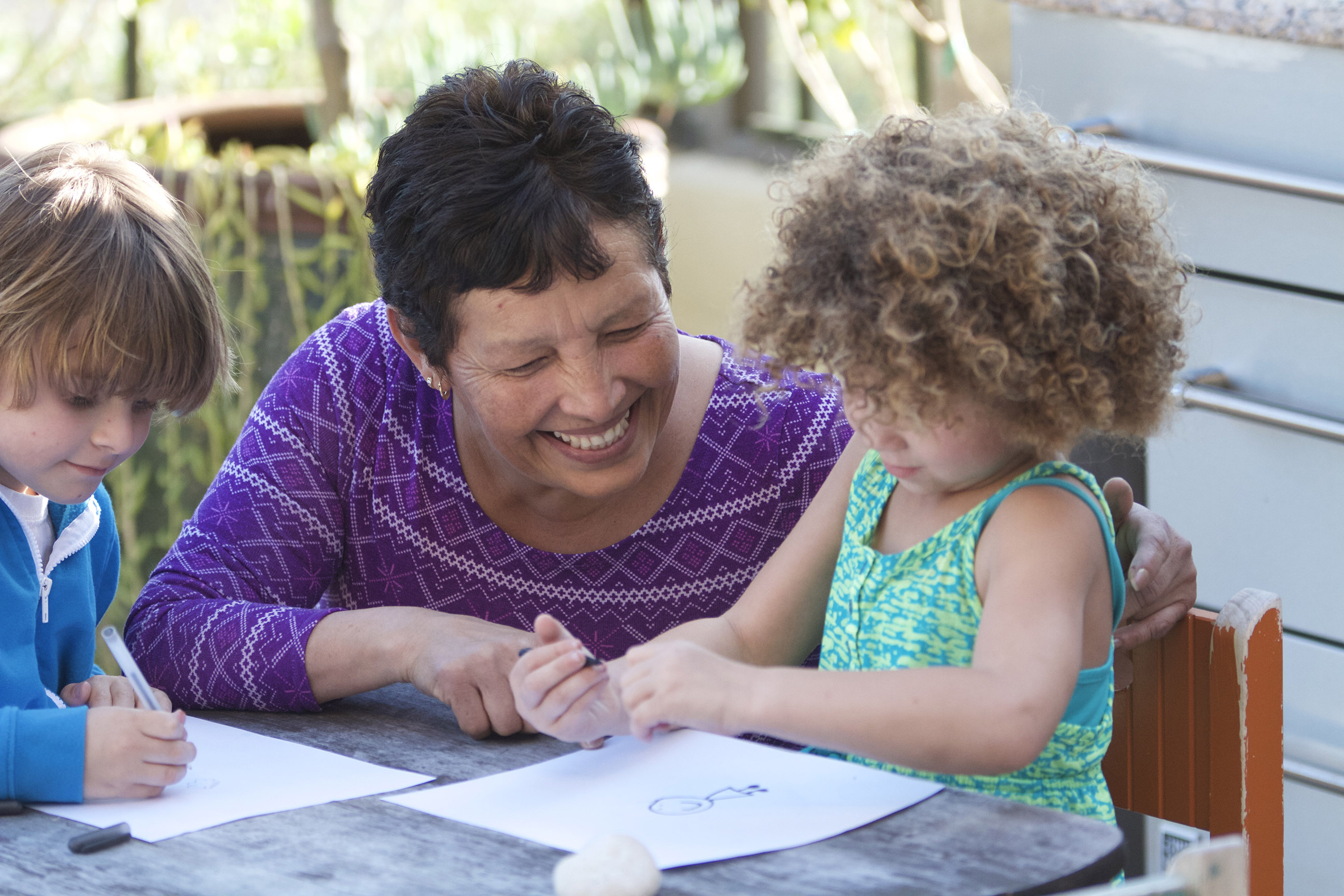 Child care provider helping two toddlers draw