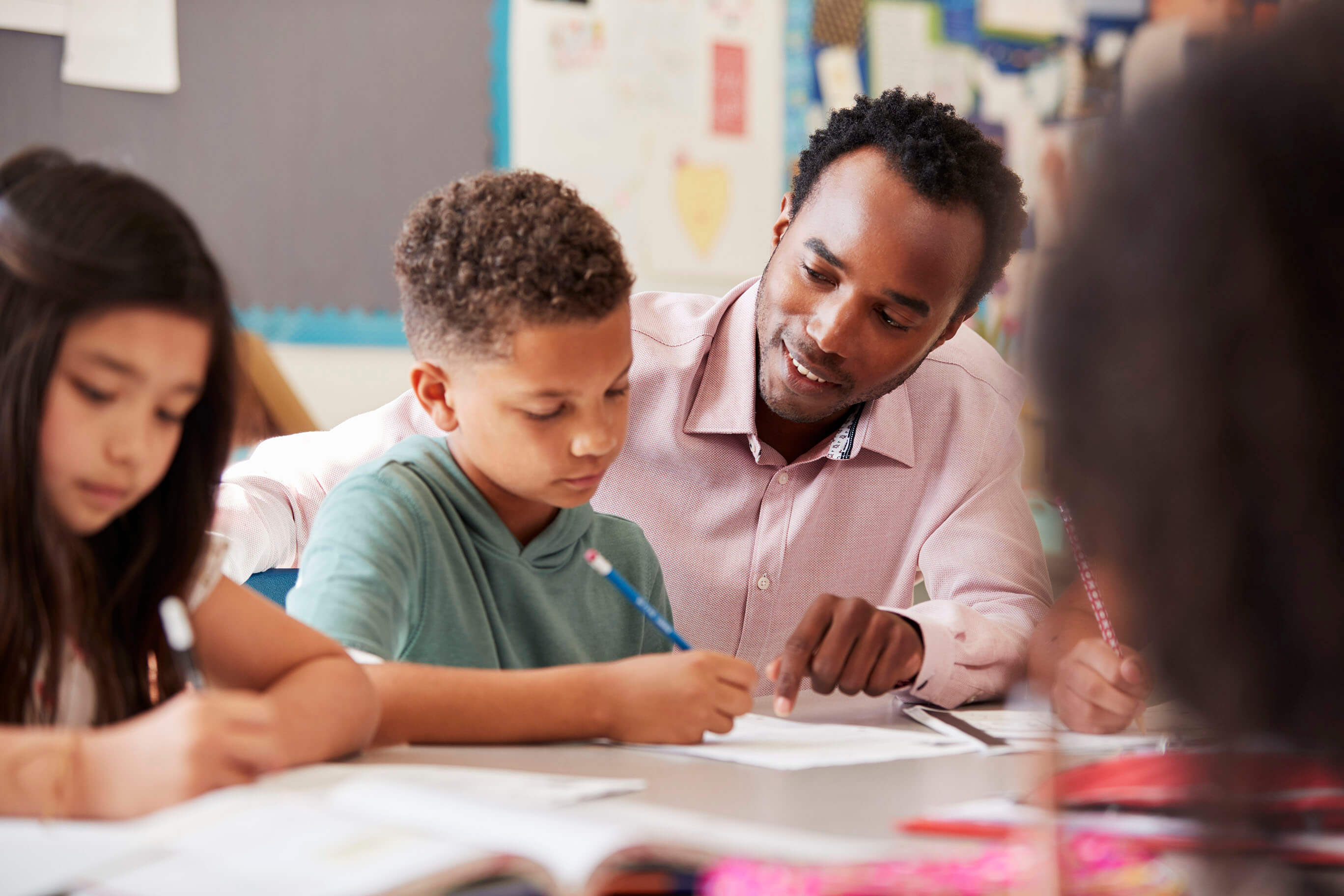 A male teacher helping students at their desks