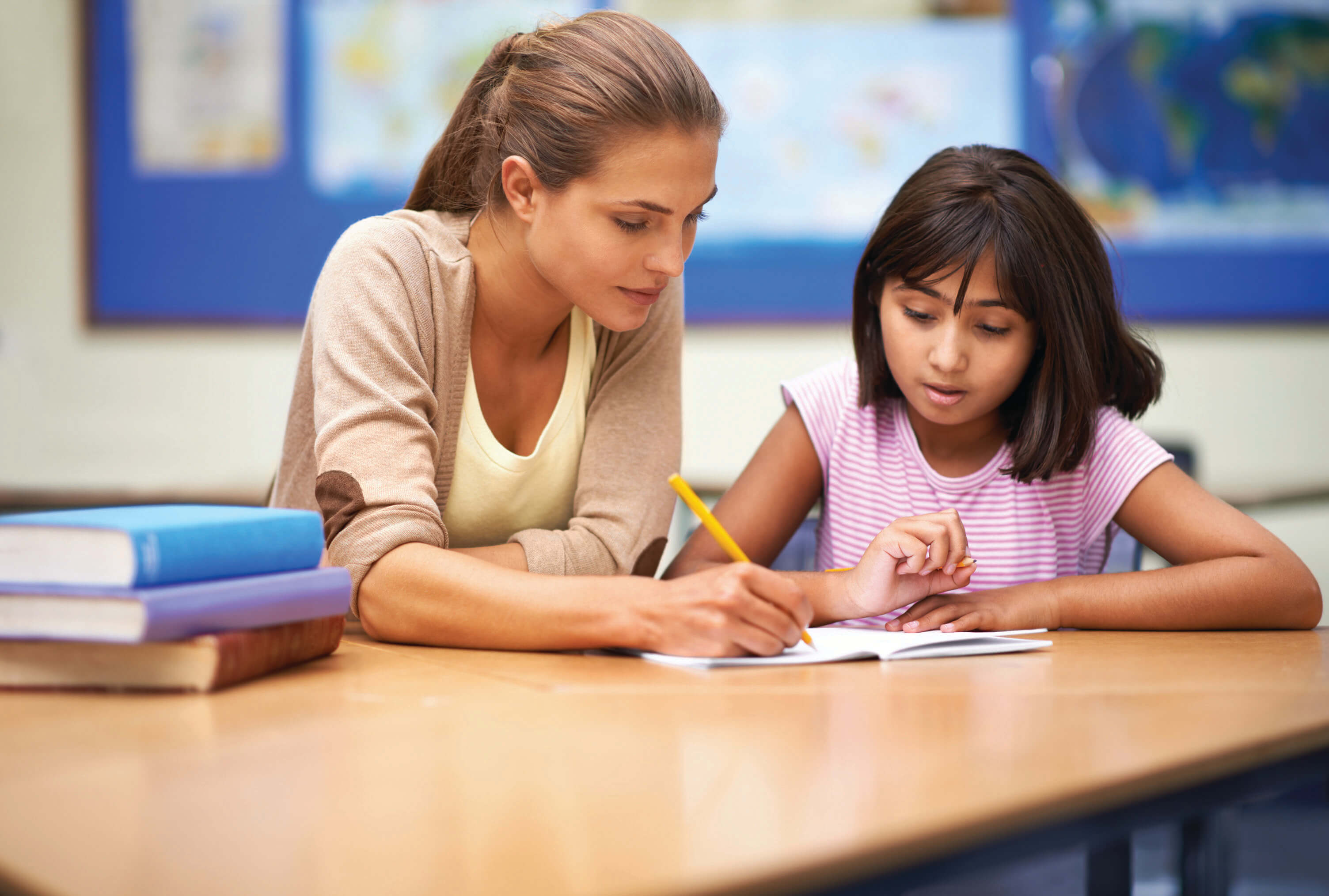 A teacher helping her student at her desk