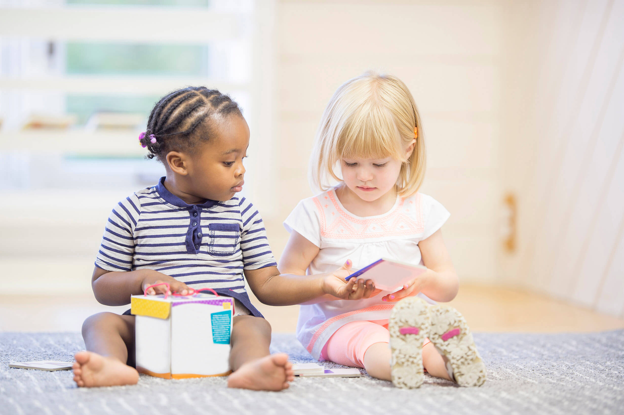 Dos niños pequeños sentados en el suelo jugando con juguetes