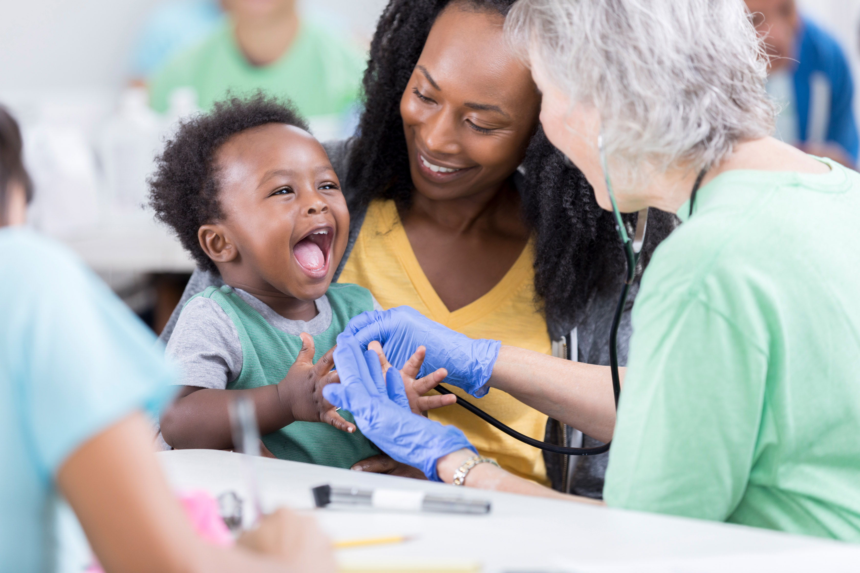 A woman holding her child that is getting checked out by a nurse